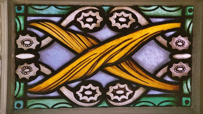 Das Bild zeigt ein farbenfrohes Buntglasfenster mit komplexen Mustern.