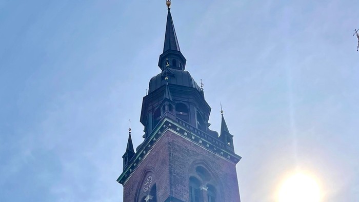 En høj kirke med to spire og solskin.