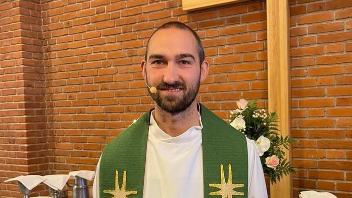 Mand i kirkeklæder foran alter.