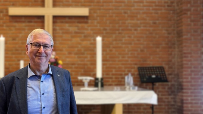 En mand står i en kirke foran en altertavle.