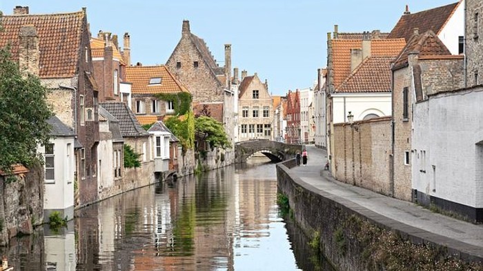 Ein schmaler Kanal durchzieht eine malerische europäische Stadt mit alten Gebäuden und rot gedeckten Dächern.