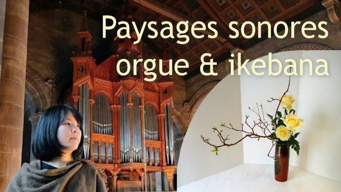 Une femme contemple un orgue tandis qu’un arrangement floral d’ikebana est exposé à ses côtés dans un cadre architectural majestueux.
