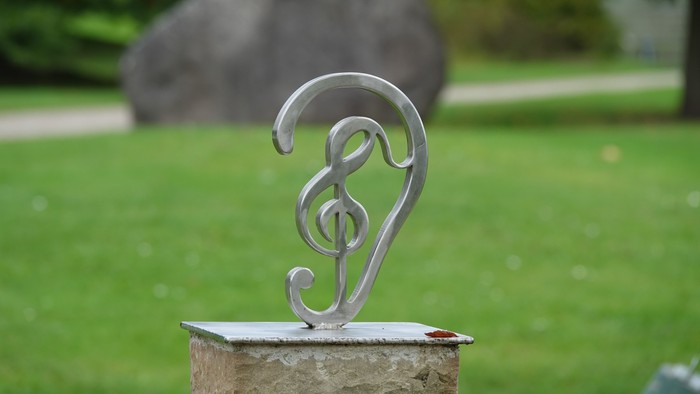 Ein silbernes Musiksymbol auf einem Stein im grünen Garten.