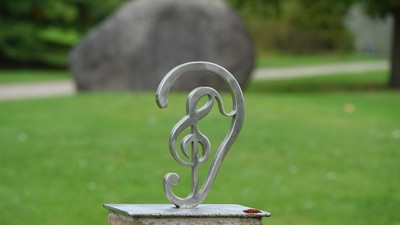 Ein silbernes Musiksymbol auf einem Stein im grünen Garten.