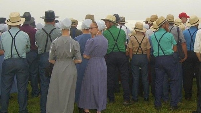 Eine Gruppe von Menschen in traditioneller Amish-Kleidung, die gemeinsam im Freien stehen.