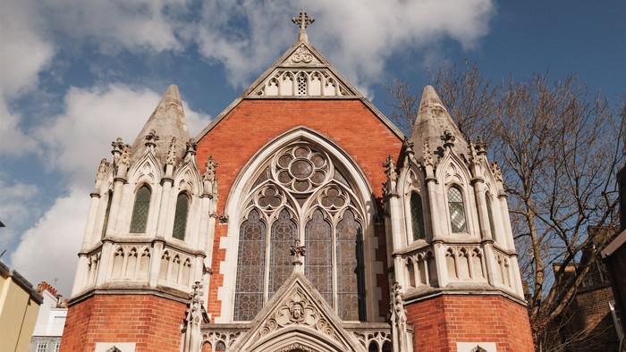 Historische Backsteinkirche mit gotischen Architekturelementen und einem markanten Buntglasfenster.