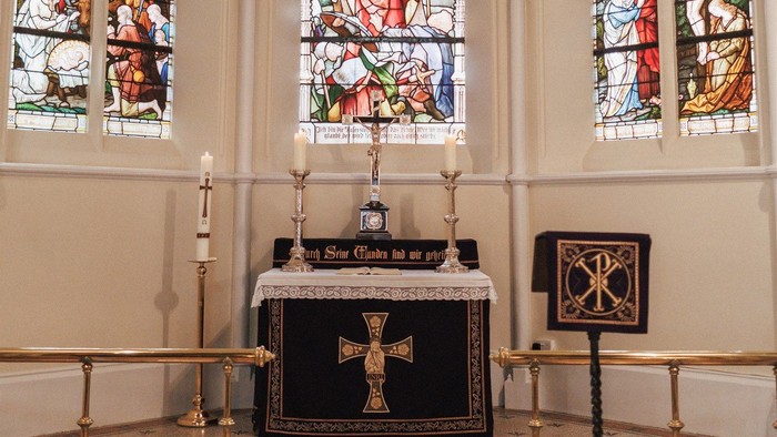 Gotische Kapelle im Innenraum mit farbenprächtigen Buntglasfenstern und einem zentralen Altar mit religiösen Artefakten.