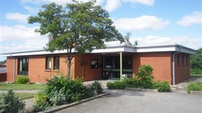 Ein modernes Einfamilienhaus mit rotem Backstein und großen Fenstern, umgeben von gepflegtem Grün.