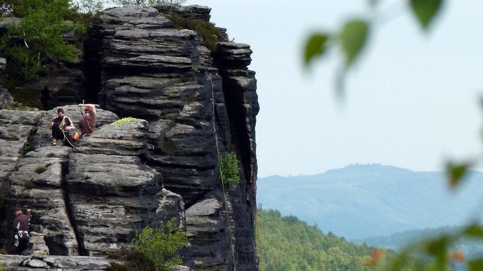 Kletterer auf felsigem Vorsprung in bergiger Landschaft