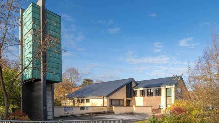 Modernes Gebäude mit grünem Turm und Parkplatz im Vordergrund