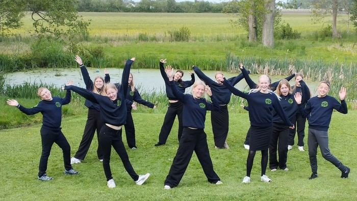 En gruppe af unge kvinder udfører en dans i en park.