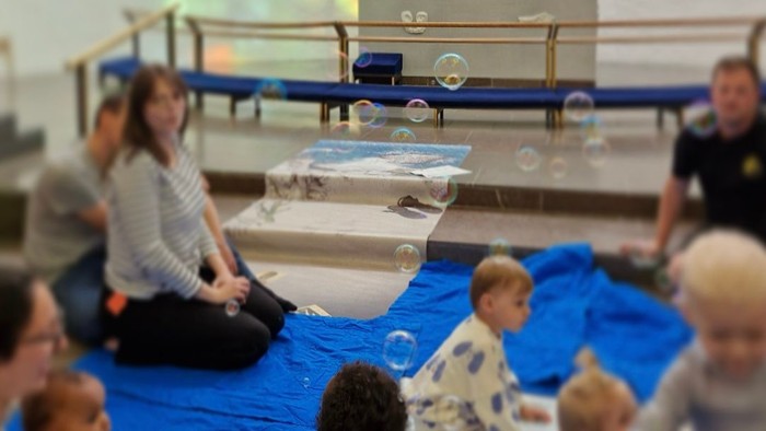 Børn spiller med boblebåde i badekar under opmærksomhed af voksne.