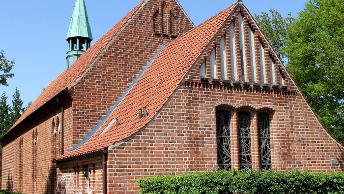 Røde teglkirke med spiret og vindrosen på en klar dag