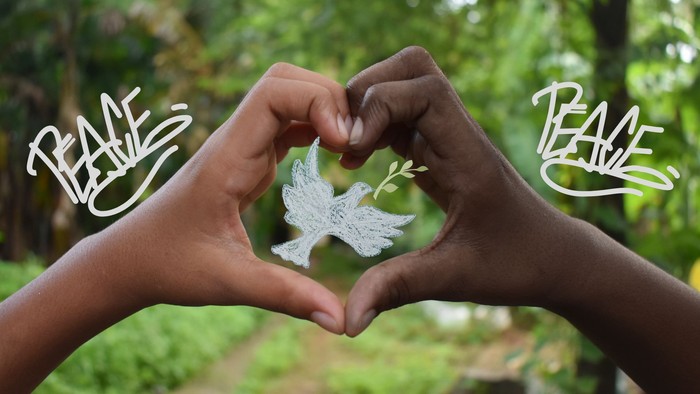 Hände formen eine Herzform mit einer Taube und einem Olivenzweig, umgeben vom Wort „Frieden“ auf beiden Seiten.