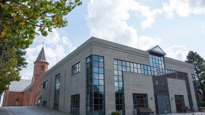 Et moderne bygning med store vinduer og en tårnagtig struktur ved siden af