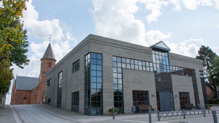 Moderne bygning med store vinduer og tårn ved siden.