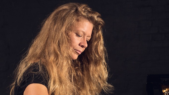 En kvinde med lang blond hår spiller piano.