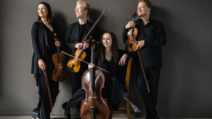 Et kvartet musikere med strygeinstrumenter, der poserer sammen i en professionel setting.