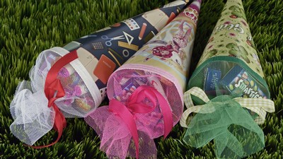 Drei Geschenke in Papierrollen mit Schleifen auf grünem Hintergrund