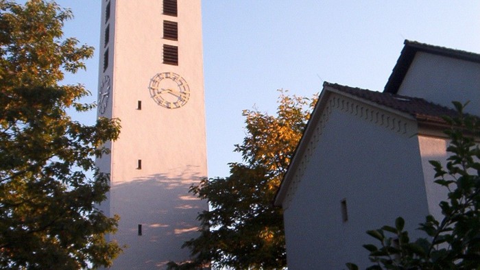 Weiße Kirche mit hohem Turm und Uhr.
