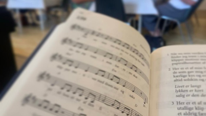 En åben bog med noter og tekst på dansk.