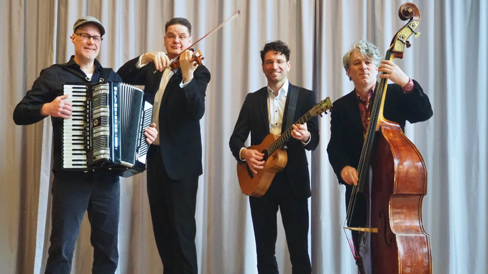 Un quatuor de musiciens jouant de l'accordéon, du violon, de la guitare et de la contrebasse ensemble sur scène.