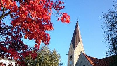 En kirke med tårn og røde løv fra en træ.