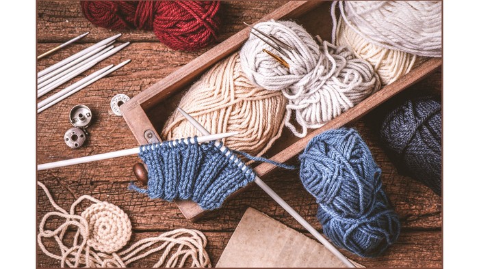 Es sind mehrere Wollknäuel und Stricknadeln zu sehen- Symbole für unsere Strickgruppe