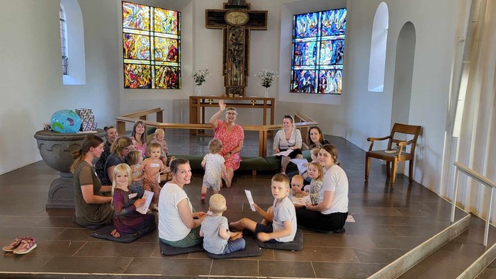 En gruppe af mennesker og børn sidder i en kirke og deltager i en aktivitet