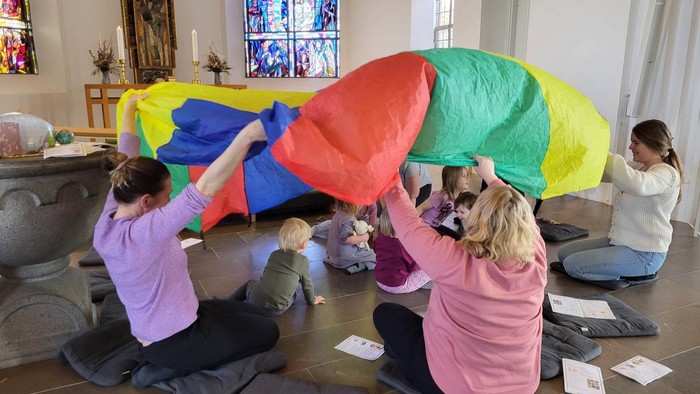 Børn spiller med farverige paraply i kirke.