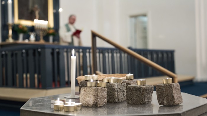 En altertavle med lysestage og stenblokke i kirke