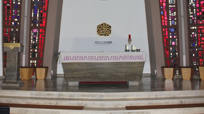 Die Kirche mit Altarraum, Kreuz und buntem Glasfenster