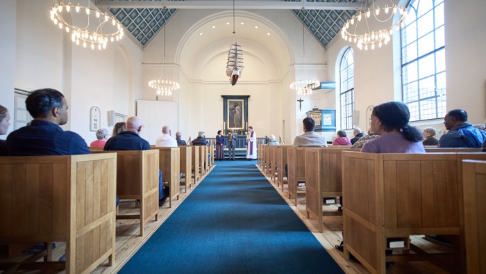 En kirke med folk, der sidder på bænke.