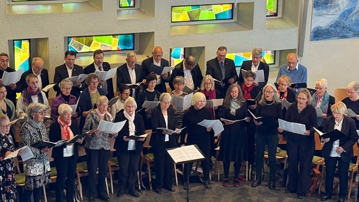 Eine vielfältige Gruppe von Sängerinnen, Sängern und Musikerinnen und Musikern, die gemeinsam in einer Kirche oder einem Konzertsaal auftreten.