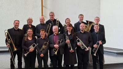 Eine Gruppe von Blechbläsern, die in formeller Kleidung mit ihren Instrumenten posieren.