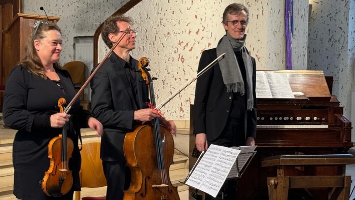 Musiker, die Saiteninstrumente und Klavier in einem dekorierten Innenraum spielen.