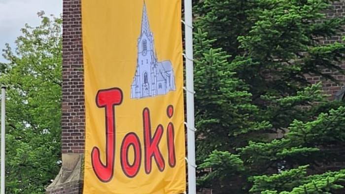 Bunter Fahnenmast mit Werbung für Joki vor Backsteingebäude