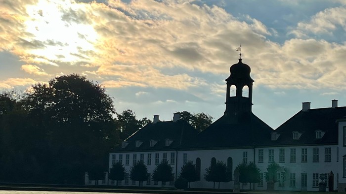 Solnedgang over en stor bygning nær vandet