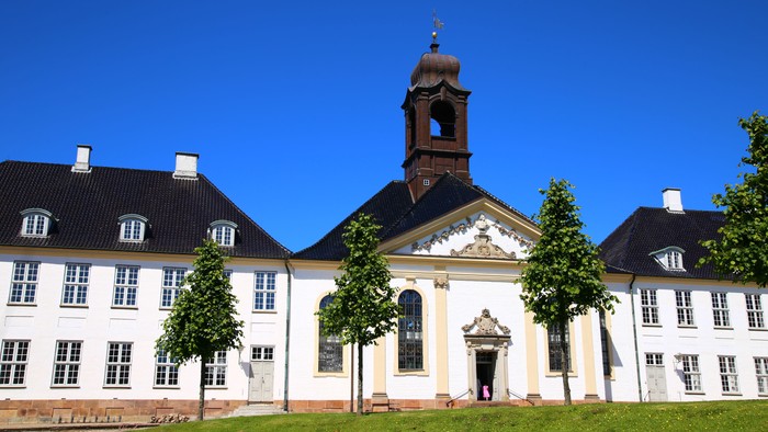 Det store og hvide slot med tårn og træer foran