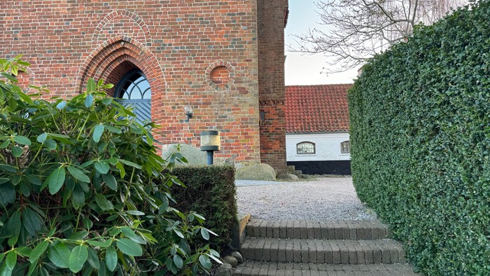 En murstensbygning med arkadevinduer og en trappe ned til en gravlæggede area.