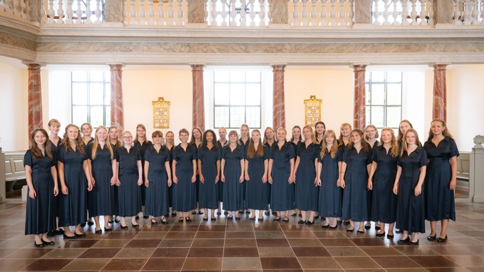 Gruppe af kvinder i blå kjoler, der poserer indendørs.