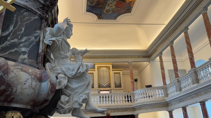 Barok kirkeinteriør med prægtige marmorstatuer, et stort orgel og detaljerede loftsfresker.