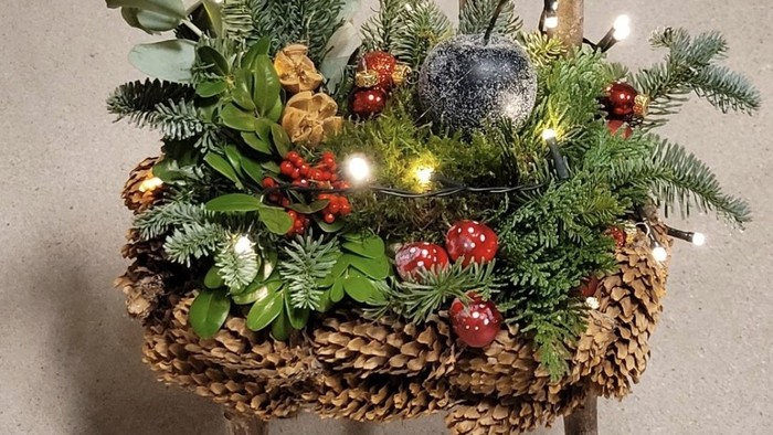 En juledekoreret stol med grønne planter og lys.