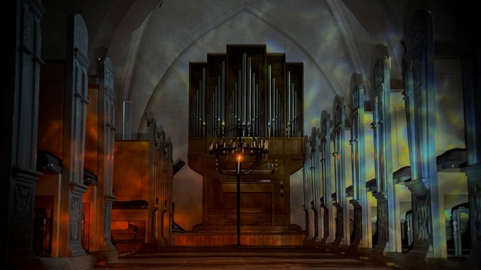 En stor kirkeorg i en mørk og dramatisk belyst kirke.