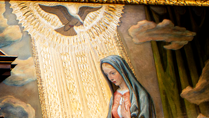 Religiøst kunstværk med engel og Jomfru Maria, der flankerer prægtige trædøre.