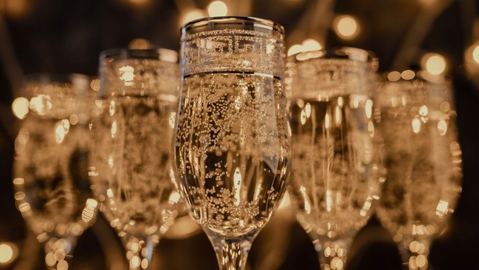 Flere champagneglas fyldt med boblerig væske, arrangeret tæt sammen, sandsynligvis til en fejring eller begivenhed.