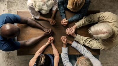 Eine Gruppe von Menschen sitzt im Kreis und hält sich an den Händen.