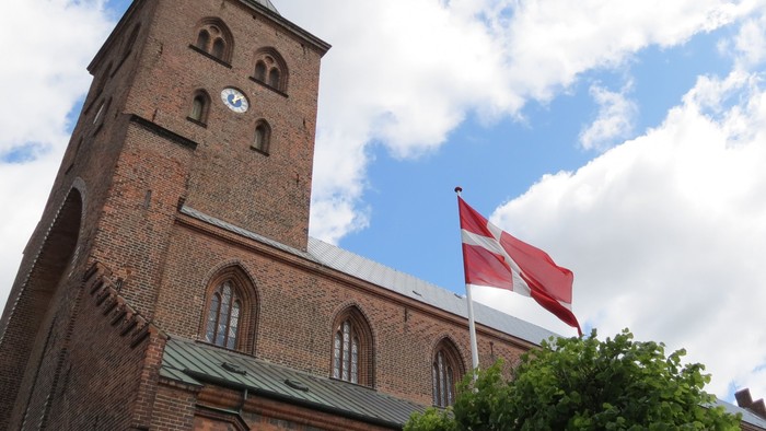 Tårn med klokke og dansk flag på kirke