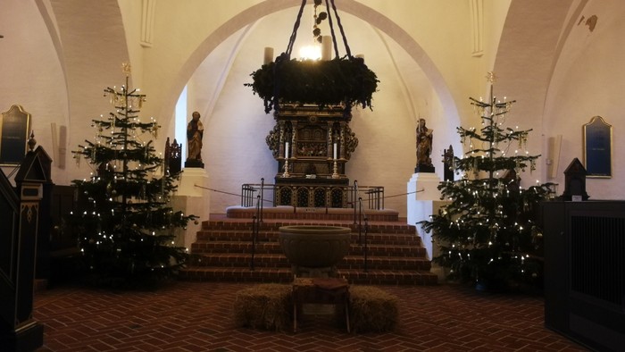 Indre del af kirke med juletømmer og alter.