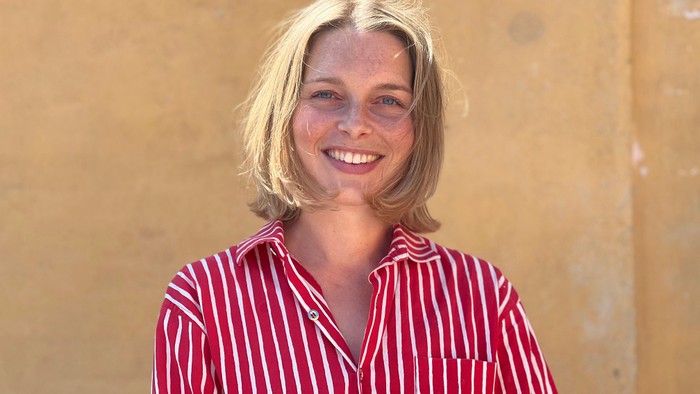 En kvinde med blond hår smiler til kameraet.